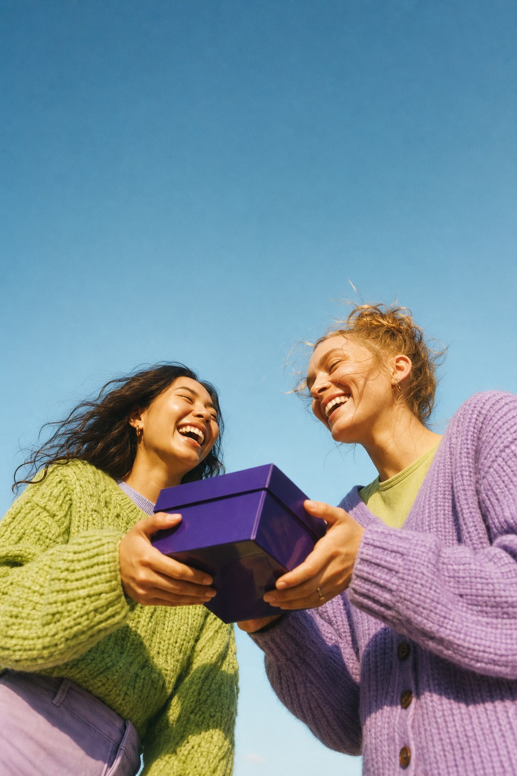 Two friends exchanging a violet gift box